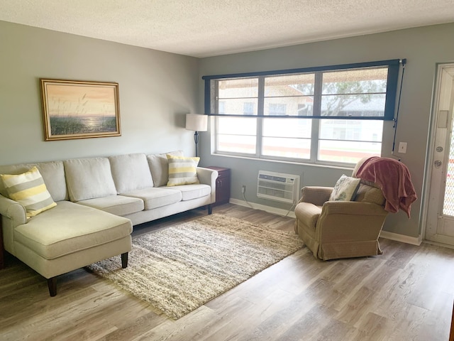 living room with an AC wall unit, a textured ceiling, and hardwood / wood-style floors