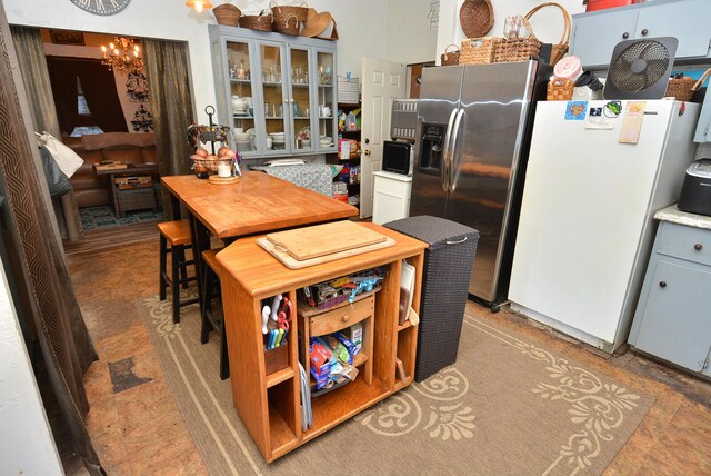 kitchen with white refrigerator, gray cabinets, stainless steel fridge, and a chandelier