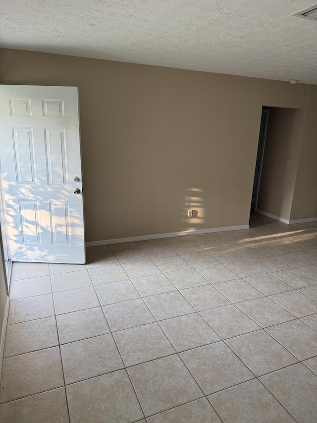 empty room featuring a textured ceiling and light tile patterned floors