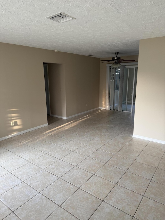 tiled spare room with a textured ceiling and ceiling fan