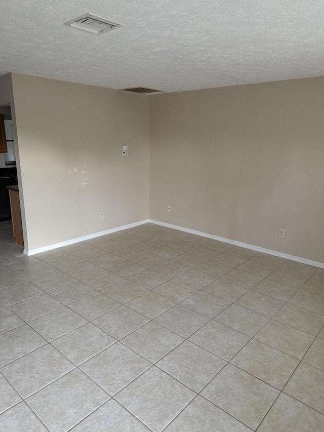 tiled spare room featuring a textured ceiling