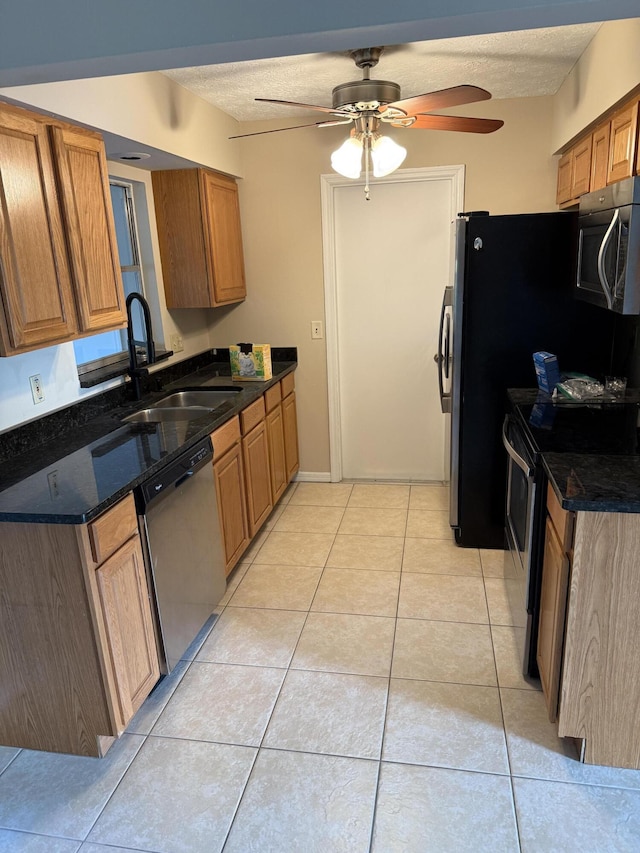 kitchen with a textured ceiling, ceiling fan, appliances with stainless steel finishes, and light tile patterned floors