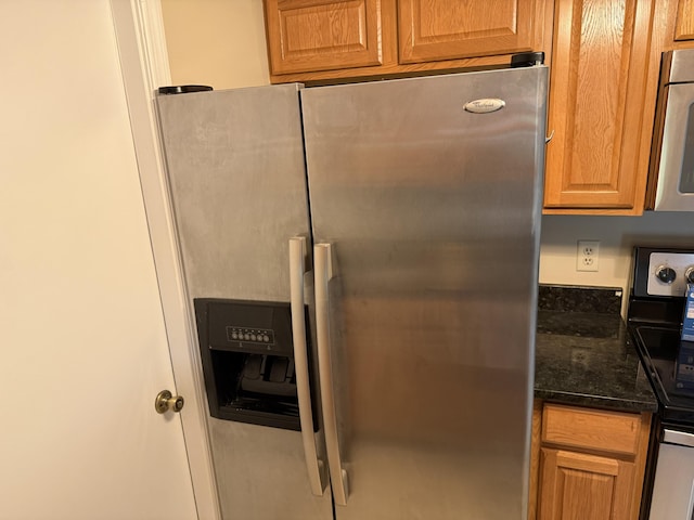 interior space with stainless steel refrigerator with ice dispenser and dark stone countertops