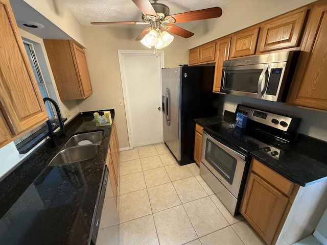 kitchen featuring ceiling fan, sink, appliances with stainless steel finishes, a textured ceiling, and light tile patterned floors