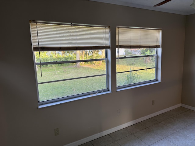 empty room with ceiling fan, crown molding, a healthy amount of sunlight, and tile patterned flooring