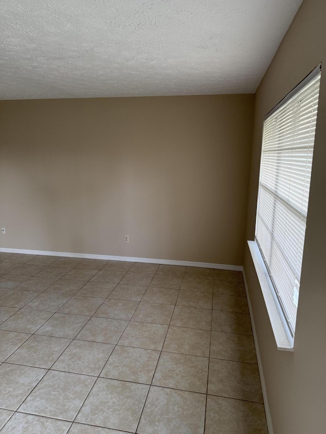 tiled empty room featuring a textured ceiling