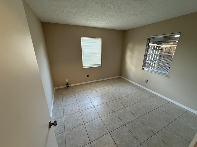 unfurnished room featuring a textured ceiling and light tile patterned flooring