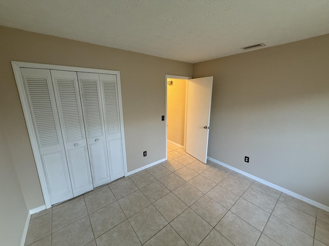 unfurnished bedroom with light tile patterned floors, a closet, and a textured ceiling