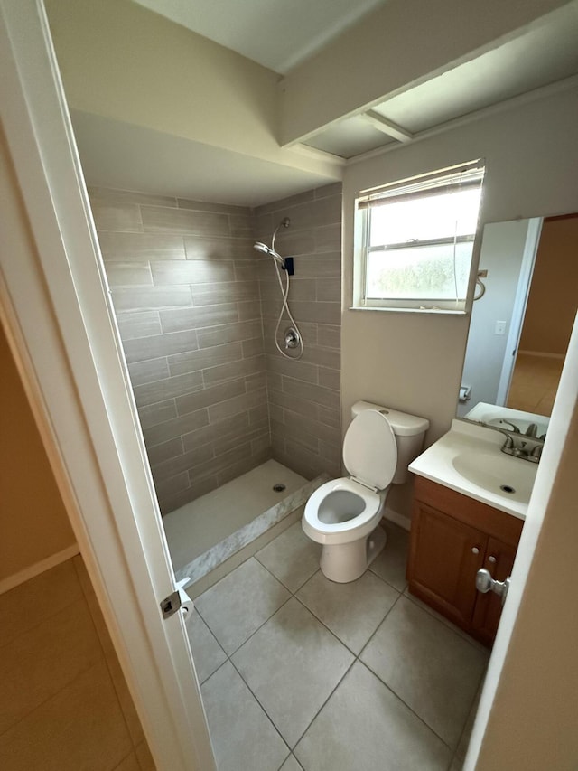 bathroom with toilet, vanity, tile patterned floors, and a tile shower