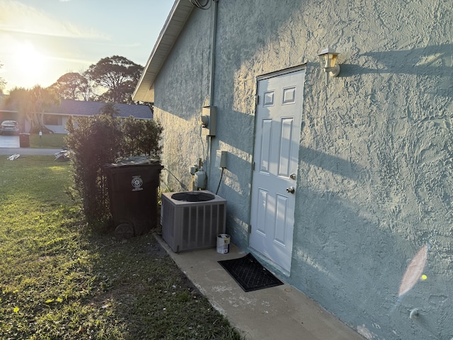 property entrance featuring central AC unit and a lawn