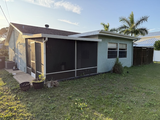 view of property exterior with a sunroom, a lawn, and central AC