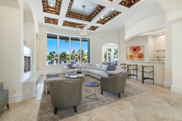 living room featuring a high ceiling, an inviting chandelier, a wealth of natural light, and coffered ceiling