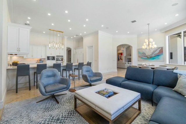 living room with ceiling fan with notable chandelier and crown molding