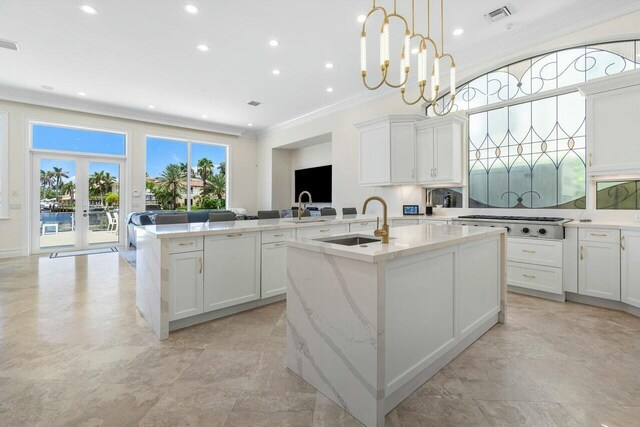 kitchen with light stone countertops, sink, hanging light fixtures, and an island with sink