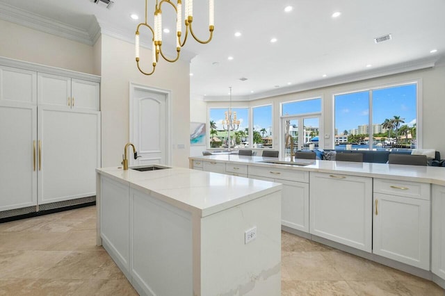 kitchen with sink, white cabinetry, a center island with sink, and an inviting chandelier