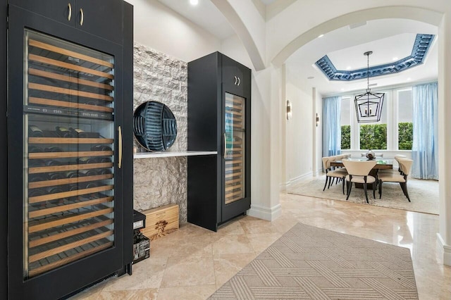 interior space featuring beverage cooler, a raised ceiling, and a notable chandelier