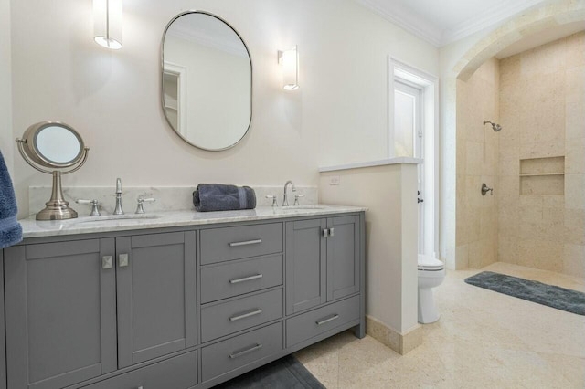 bathroom with crown molding, toilet, vanity, and a tile shower