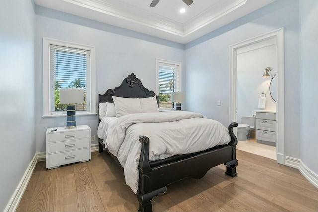 bedroom with ceiling fan, crown molding, a tray ceiling, and light hardwood / wood-style floors