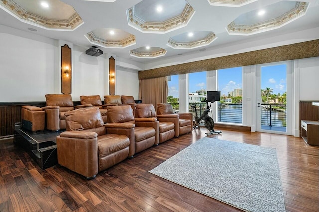 home theater room with dark wood-type flooring, coffered ceiling, and ornamental molding