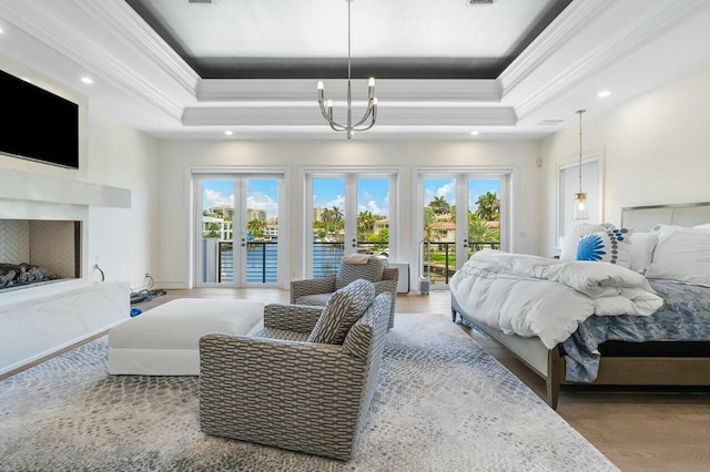 bedroom with hardwood / wood-style flooring, french doors, a tray ceiling, and multiple windows