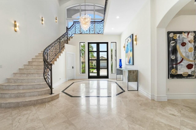 foyer entrance with a chandelier, a towering ceiling, and french doors