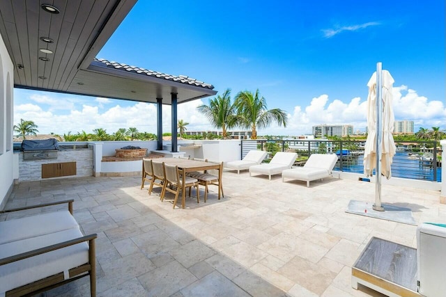 view of patio with a water view, exterior kitchen, and area for grilling