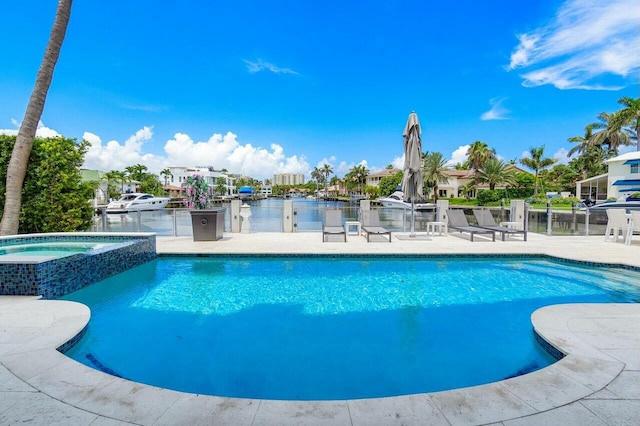 view of pool featuring an in ground hot tub, a patio area, and a water view