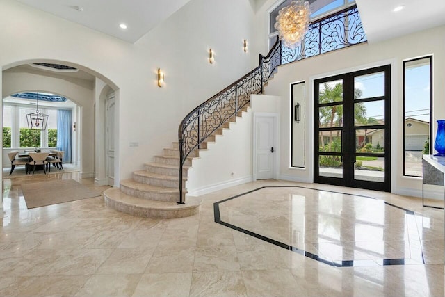 entryway featuring french doors, a high ceiling, and a chandelier