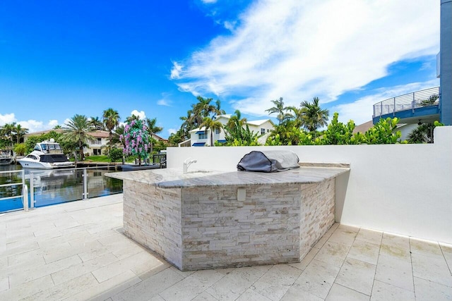 view of patio featuring area for grilling, a bar, and a water view