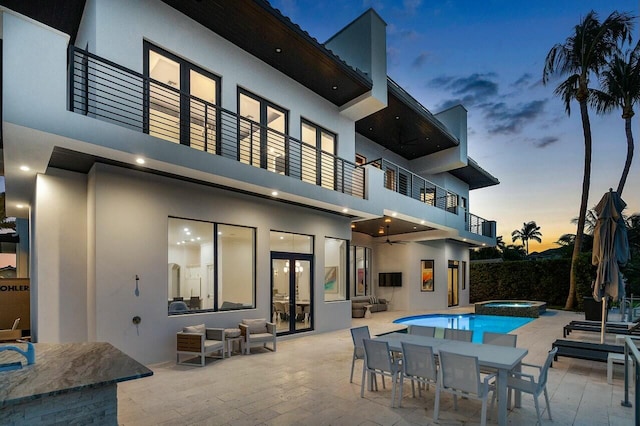 rear view of property featuring a balcony, a pool with hot tub, ceiling fan, and a patio