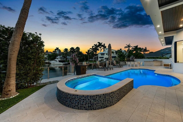 pool at dusk featuring a patio and an in ground hot tub