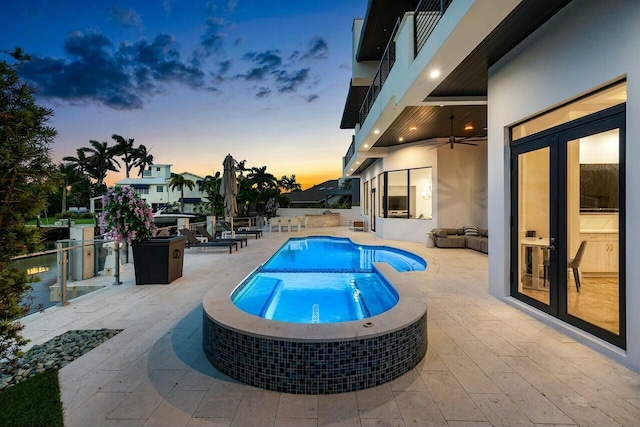 pool at dusk featuring ceiling fan, french doors, a patio area, and an in ground hot tub