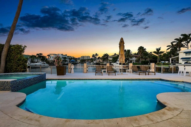 pool at dusk with a water view, a patio, and an in ground hot tub