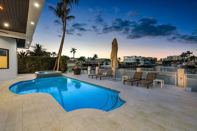 pool at dusk with a patio and an in ground hot tub