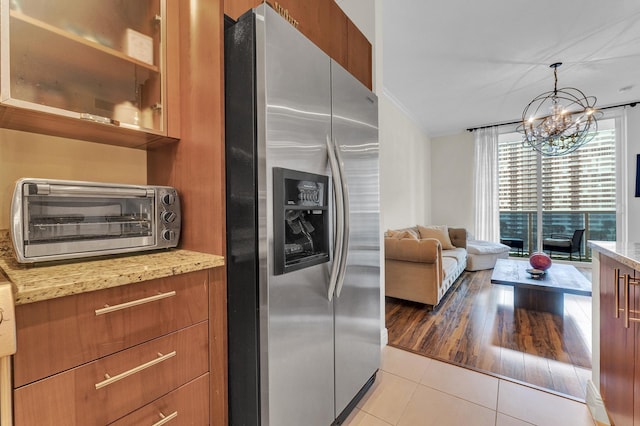 kitchen featuring stainless steel fridge with ice dispenser, light stone countertops, hanging light fixtures, and light tile patterned floors