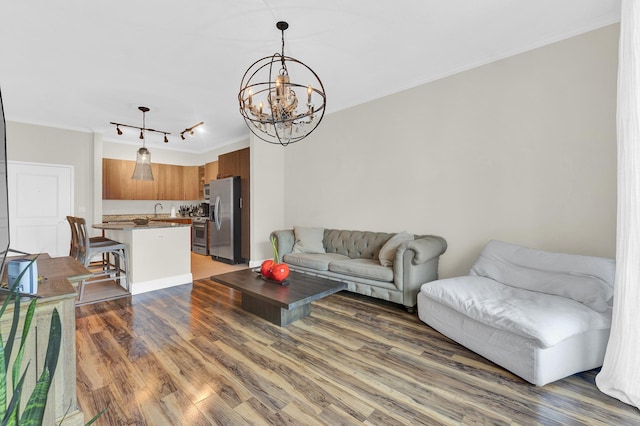 living room with sink, crown molding, a notable chandelier, and dark hardwood / wood-style flooring