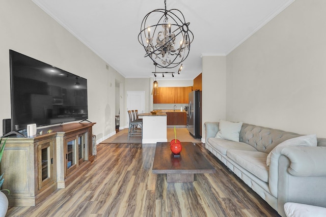 living room with sink, dark hardwood / wood-style flooring, ornamental molding, and a chandelier