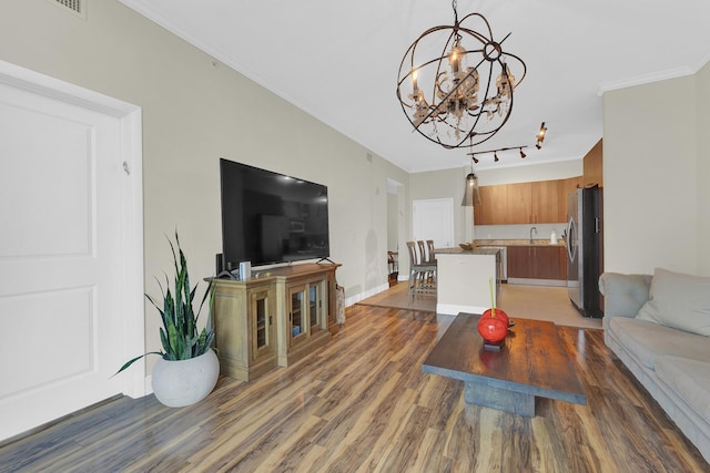 living room featuring sink, dark hardwood / wood-style floors, crown molding, and a notable chandelier