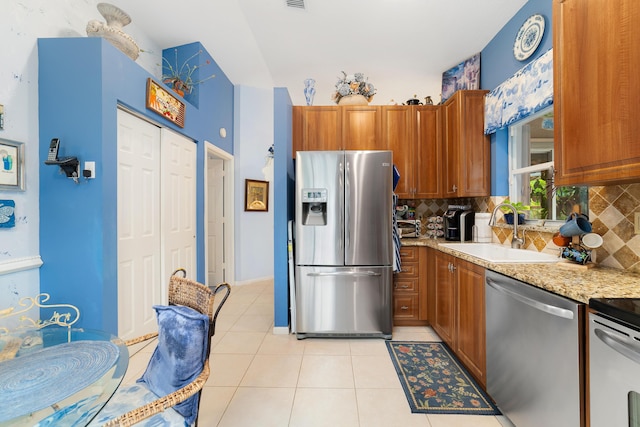 kitchen with light tile patterned flooring, appliances with stainless steel finishes, tasteful backsplash, and sink