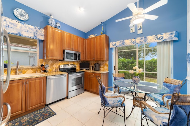 kitchen featuring lofted ceiling, decorative backsplash, sink, light stone countertops, and stainless steel appliances