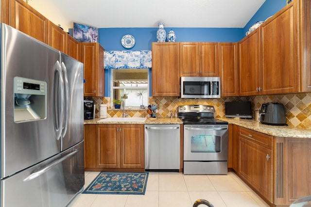 kitchen featuring stainless steel appliances, tasteful backsplash, sink, light stone counters, and light tile patterned floors