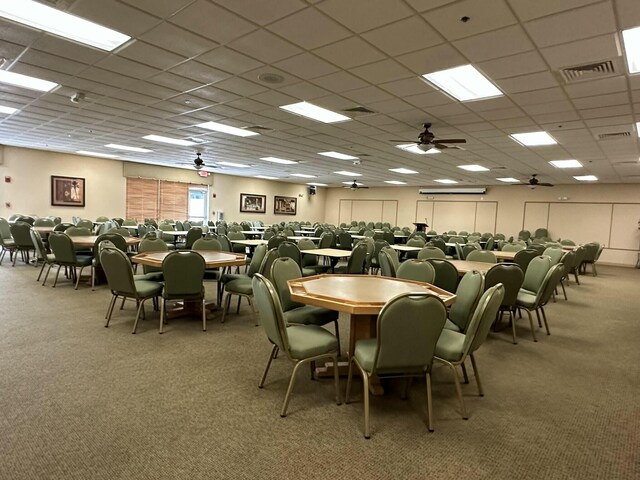 carpeted dining area featuring a paneled ceiling and ceiling fan