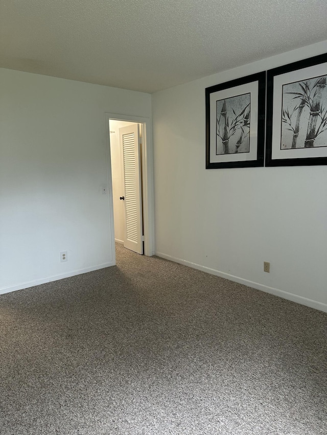 unfurnished room with carpet and a textured ceiling