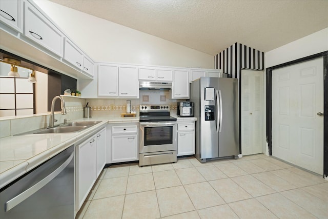 kitchen with white cabinets, appliances with stainless steel finishes, lofted ceiling, sink, and light tile patterned floors