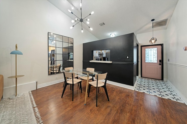 dining room featuring lofted ceiling, wood-type flooring, a chandelier, and a textured ceiling