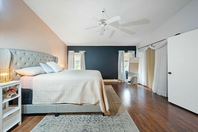 bedroom featuring ceiling fan, vaulted ceiling, dark wood-type flooring, and a textured ceiling