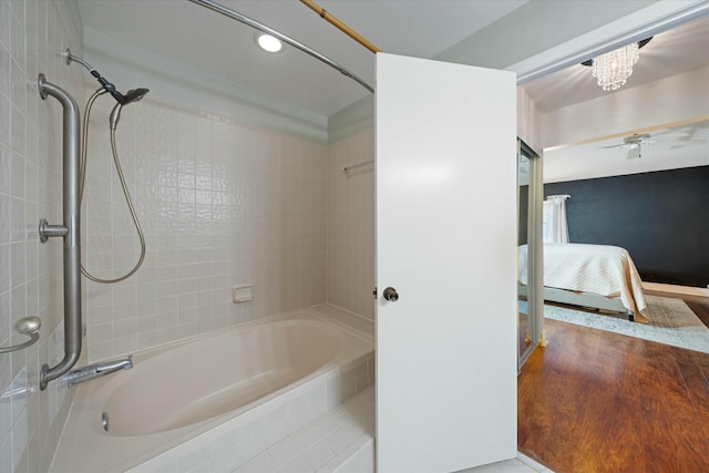 bathroom featuring tiled shower / bath, wood-type flooring, and ceiling fan with notable chandelier