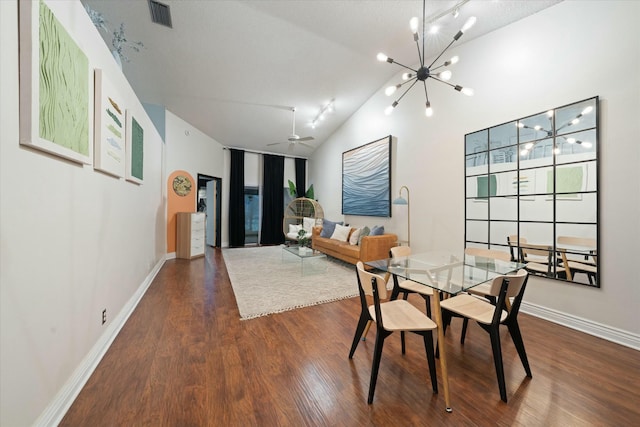 dining room with ceiling fan with notable chandelier, a textured ceiling, dark hardwood / wood-style flooring, and vaulted ceiling