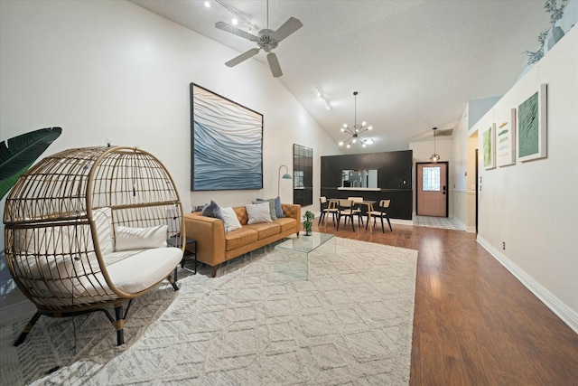 living room with vaulted ceiling, ceiling fan with notable chandelier, and hardwood / wood-style flooring