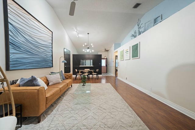 living room with lofted ceiling, wood-type flooring, and ceiling fan with notable chandelier